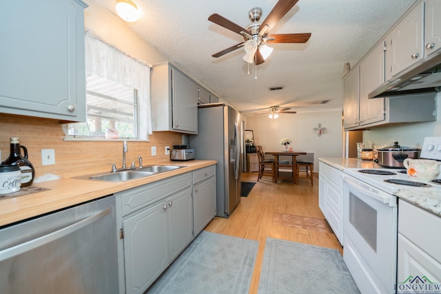 kitchen featuring a textured ceiling, stainless steel appliances, light hardwood / wood-style flooring, and sink