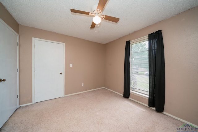 unfurnished room with ceiling fan, light colored carpet, and a textured ceiling