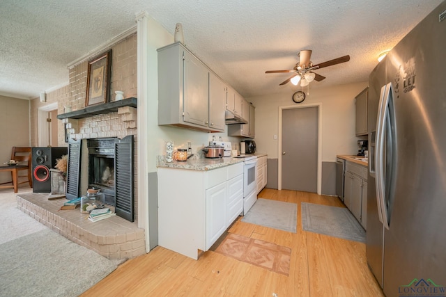 kitchen with white range with electric cooktop, stainless steel fridge, light hardwood / wood-style floors, and a textured ceiling