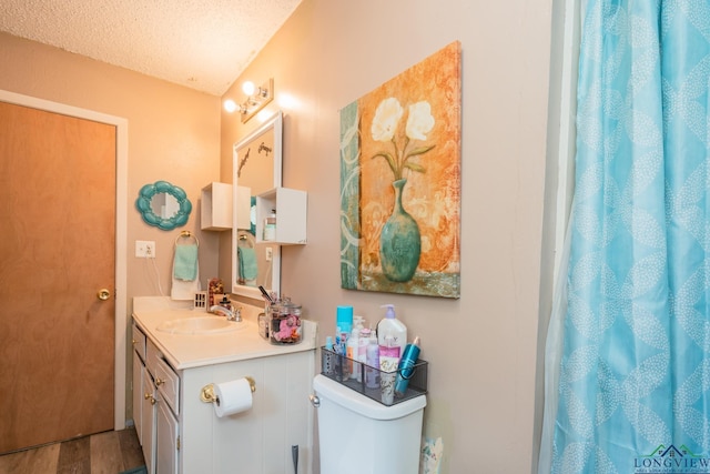 bathroom with vanity, toilet, wood-type flooring, and a textured ceiling