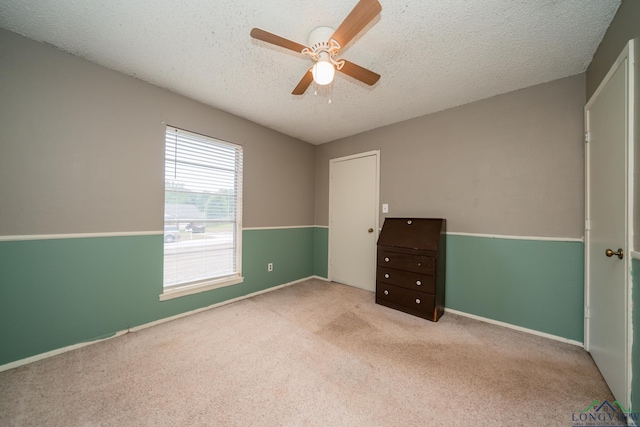 carpeted spare room with ceiling fan and a textured ceiling