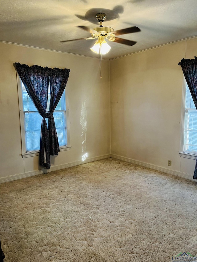 empty room with ceiling fan, light colored carpet, a healthy amount of sunlight, and a textured ceiling