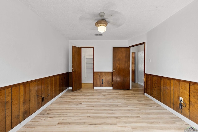 unfurnished room featuring light wood-type flooring, a textured ceiling, and ceiling fan