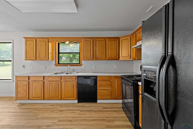 kitchen featuring sink, black appliances, and light wood-type flooring