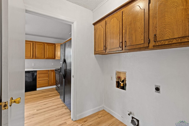 clothes washing area featuring electric dryer hookup, gas dryer hookup, hookup for a washing machine, light hardwood / wood-style floors, and a textured ceiling