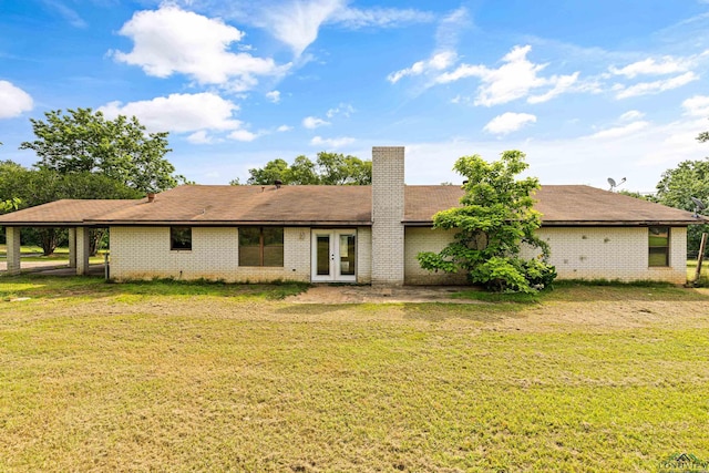 rear view of house featuring a lawn, a carport, and french doors