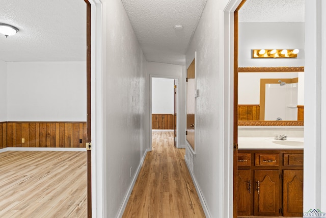 corridor featuring a textured ceiling, light hardwood / wood-style flooring, and sink