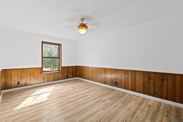 spare room with a textured ceiling, light hardwood / wood-style flooring, and ceiling fan