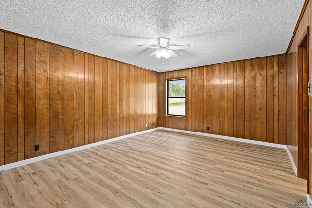 spare room with wood walls, ceiling fan, and light wood-type flooring