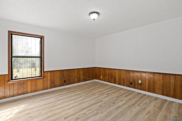 empty room with a textured ceiling and light hardwood / wood-style flooring