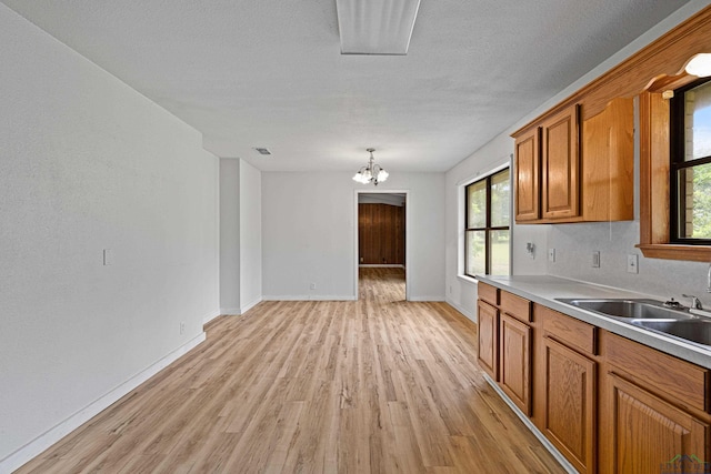 kitchen featuring pendant lighting, an inviting chandelier, a healthy amount of sunlight, and sink