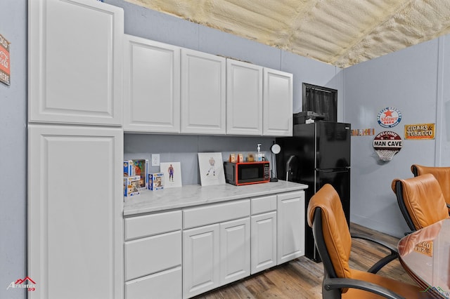 102 Poplar St, Marshall, TX 75670 - kitchen featuring white cabinets, wood finished floors, and freestanding refrigerator