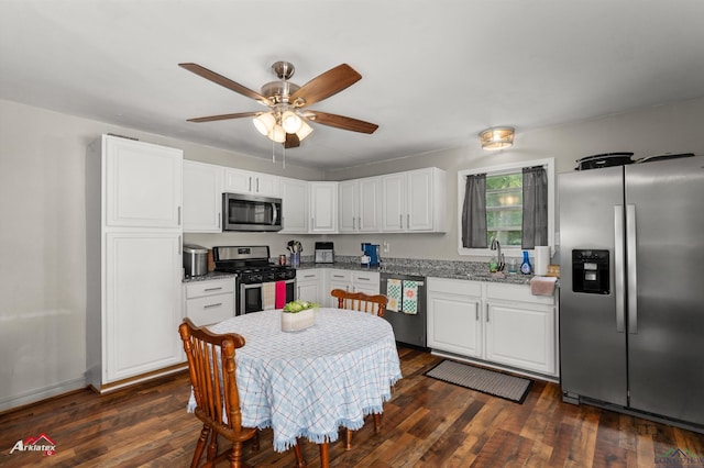 102 Poplar St, Marshall, TX 75670 - kitchen with appliances with stainless steel finishes, white cabinetry, ceiling fan, dark wood-style floors, and light stone countertops