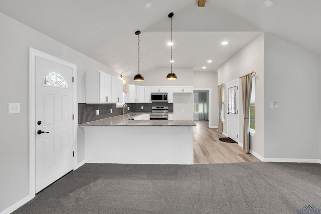 kitchen featuring pendant lighting, white cabinetry, stainless steel appliances, vaulted ceiling, and kitchen peninsula