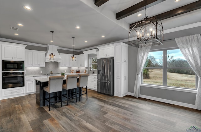 kitchen with sink, stainless steel appliances, white cabinets, a kitchen island, and decorative light fixtures