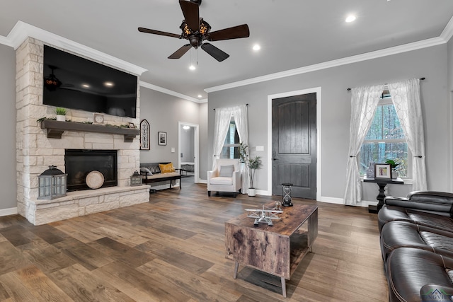 living room featuring ceiling fan, crown molding, hardwood / wood-style floors, and a fireplace