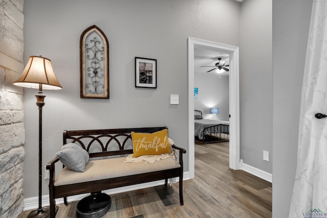 sitting room with ceiling fan and wood-type flooring