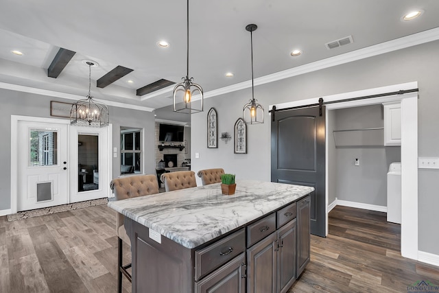 kitchen with a breakfast bar area, a center island, dark brown cabinets, hanging light fixtures, and a barn door