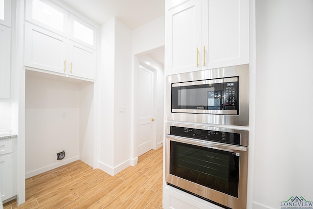 kitchen with white cabinetry, light hardwood / wood-style flooring, light stone countertops, and appliances with stainless steel finishes