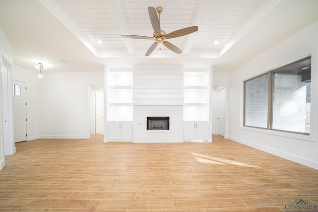 unfurnished living room featuring built in shelves, a large fireplace, light hardwood / wood-style flooring, and ceiling fan