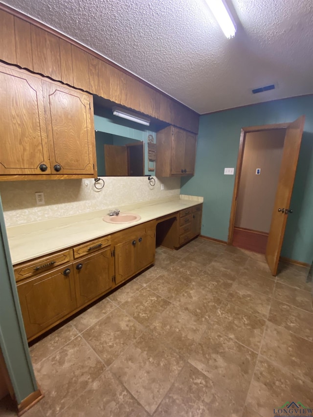 kitchen with sink, built in desk, and a textured ceiling