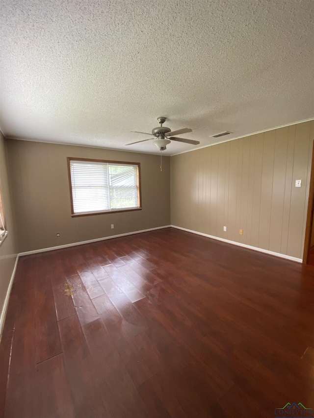 empty room featuring dark wood-type flooring, a textured ceiling, and ceiling fan