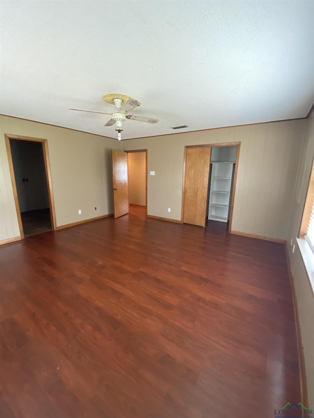 spare room featuring dark wood-type flooring, ceiling fan, and a textured ceiling