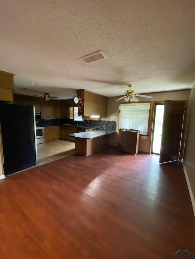 kitchen featuring dark hardwood / wood-style flooring, fridge, electric range, ceiling fan, and kitchen peninsula