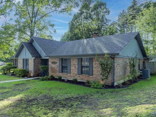 1317 Tiffany Ln, Longview, TX 75604 - single story home with cooling unit, roof with shingles, a front lawn, a chimney, and brick siding