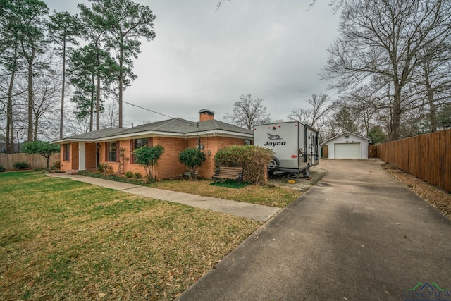 view of front facade with a front yard, fence, an outdoor structure, a detached garage, and brick siding