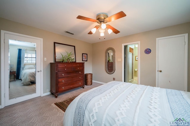 bedroom featuring visible vents, a ceiling fan, ensuite bath, baseboards, and light colored carpet