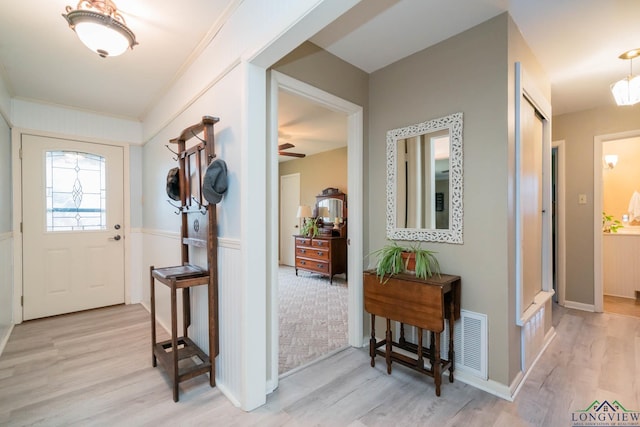 entrance foyer with visible vents, baseboards, light wood finished floors, and ornamental molding