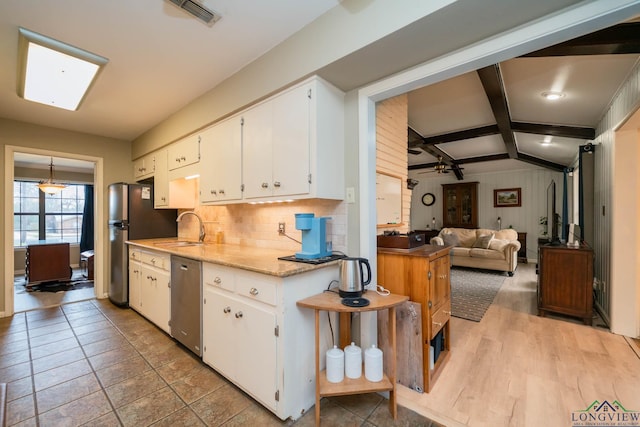 kitchen featuring visible vents, vaulted ceiling with beams, decorative backsplash, stainless steel appliances, and a sink