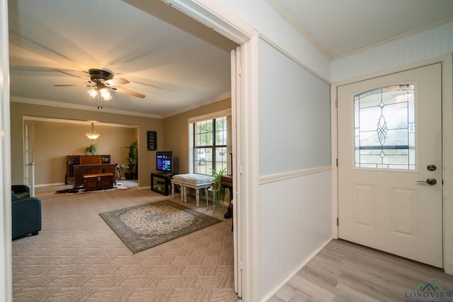 entryway with a wainscoted wall, ceiling fan, light wood-style floors, and ornamental molding