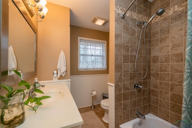 bathroom with a wainscoted wall, shower / bathtub combination with curtain, toilet, visible vents, and vanity