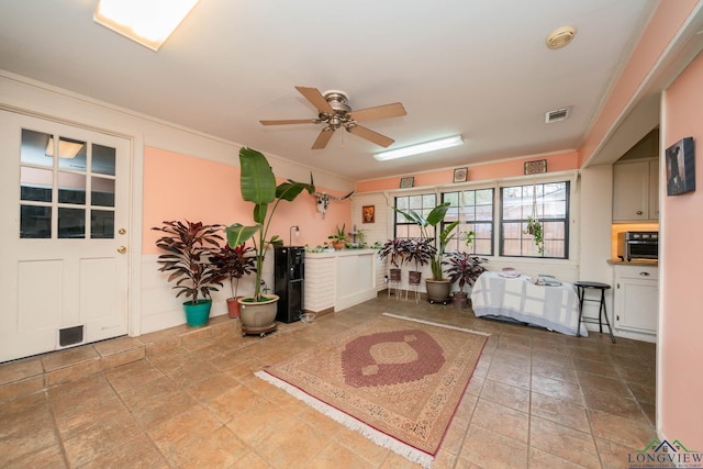 interior space with crown molding, visible vents, and ceiling fan