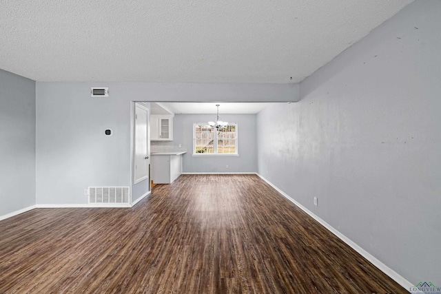 unfurnished living room with a chandelier, a textured ceiling, and hardwood / wood-style flooring