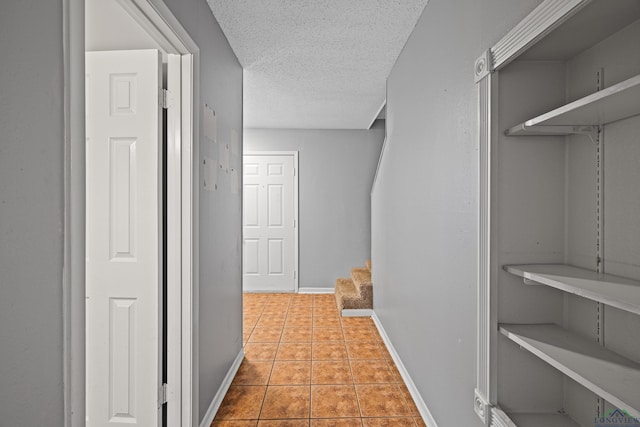 hall featuring light tile patterned floors and a textured ceiling