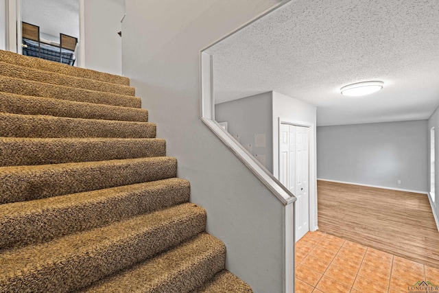 stairway featuring tile patterned flooring and a textured ceiling