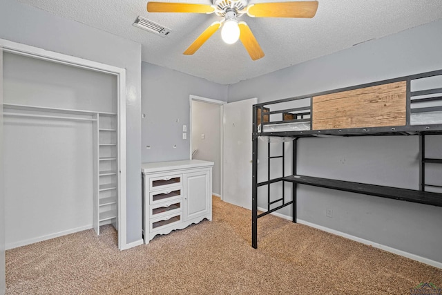 unfurnished bedroom featuring ceiling fan, light colored carpet, and a textured ceiling