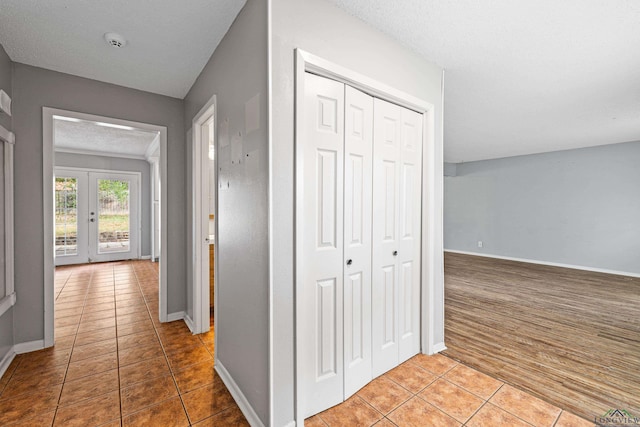 hall featuring tile patterned floors, french doors, and a textured ceiling