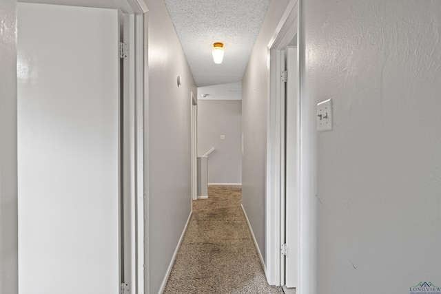 corridor featuring carpet flooring and a textured ceiling