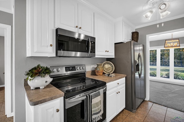 kitchen featuring white cabinets, ornamental molding, tile patterned floors, and appliances with stainless steel finishes