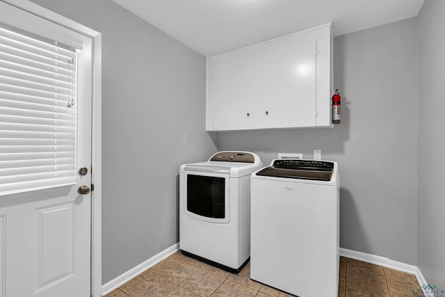 clothes washing area featuring washer and clothes dryer, light tile patterned floors, and cabinets