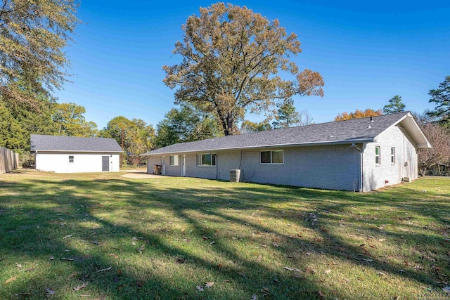 rear view of property featuring a yard and an outbuilding