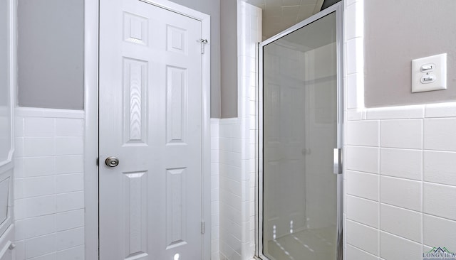 bathroom featuring a shower with shower door and tile walls