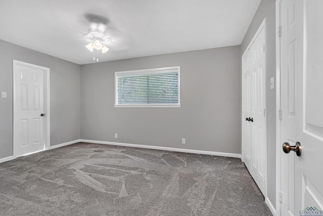 spare room featuring ceiling fan and dark carpet