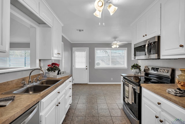 kitchen with sink, light tile patterned floors, appliances with stainless steel finishes, white cabinets, and ornamental molding