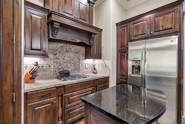 1624 Olympic Dr, Longview, TX 75605 - kitchen featuring appliances with stainless steel finishes, ventilation hood, decorative backsplash, a textured wall, and dark brown cabinetry