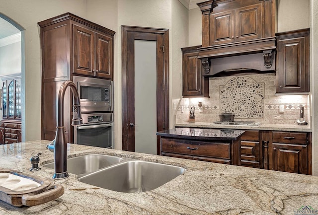 1624 Olympic Dr, Longview, TX 75605 - kitchen featuring appliances with stainless steel finishes, custom exhaust hood, tasteful backsplash, light stone counters, and arched walkways